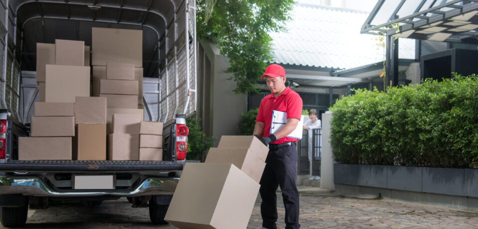 Asian delivery man in red uniform delivering parcel boxes to woman recipient at home