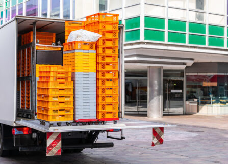 A car with plastic orange boxes for goods stands on the pedestrian zone. A car with plastic orange and white boxes for goods stands on the pedestrian zone of the city.
