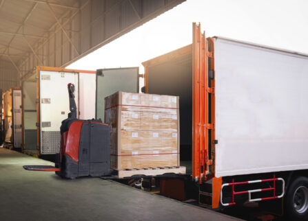 electric-forklift-loading-package-boxes-into-container-trucks-parked-loading-dock-warehouse electric-forklift-loading-package-boxes-into-container-trucks-parked-loading-dock-warehouse