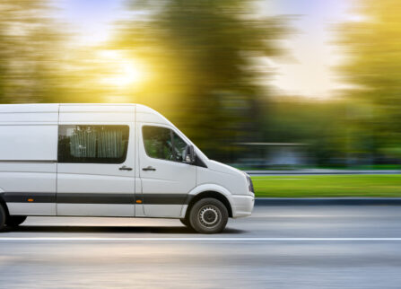 White van moving on a city road at sunset landscape background. White van moving on a city road at sunset landscape background. Small truck delivers the goods